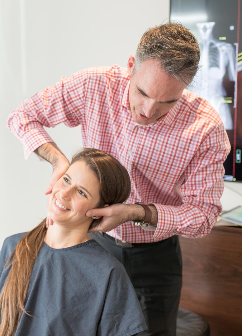 Dr Scott Campbell-Lloyd assessing a patient's neck at Mt Hawthorn Chiropractic Clinic